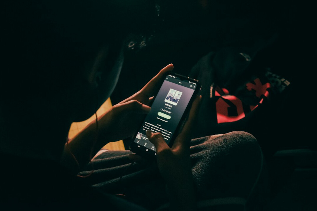 person scrolling on smartphone at night